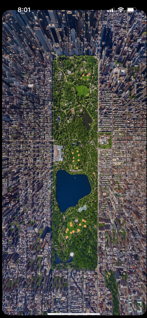 Aerial view of Central Park surrounded by city skyscrapers, showcasing green spaces and a lake.