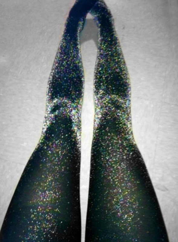 Close-up of legs wearing glittery black tights, creating a sparkling effect on a flat surface.